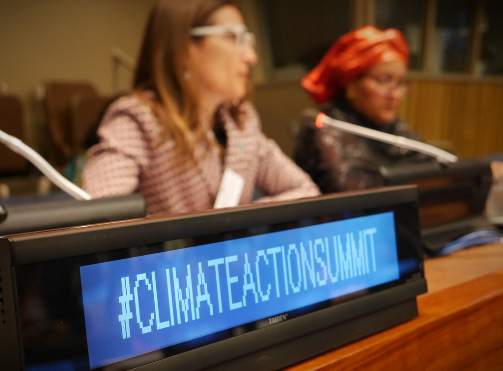 标志写着“# ClimateActionSummit。”Chilean Minister of Environment Carolina Schmidt and U.N. Deputy Secretary-General Amina J. Mohammed pictured in background.