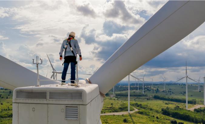 Windmill engineer wearing PPE standing on wind turbine