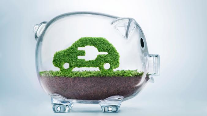 Grass growing in the shape of a car with a cut-out plug, inside a transparent piggy bank,