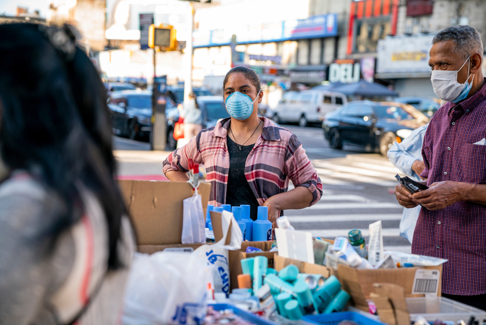 Person wearing a mask sells beauty products at a street stall in Washington Heights, Manhattan in New York City during the COVID-19 pandemic.